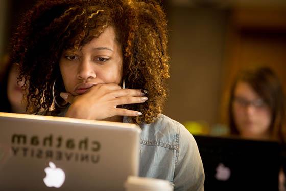 Photo of a Chatham University student looking at her laptop in a lecture hall