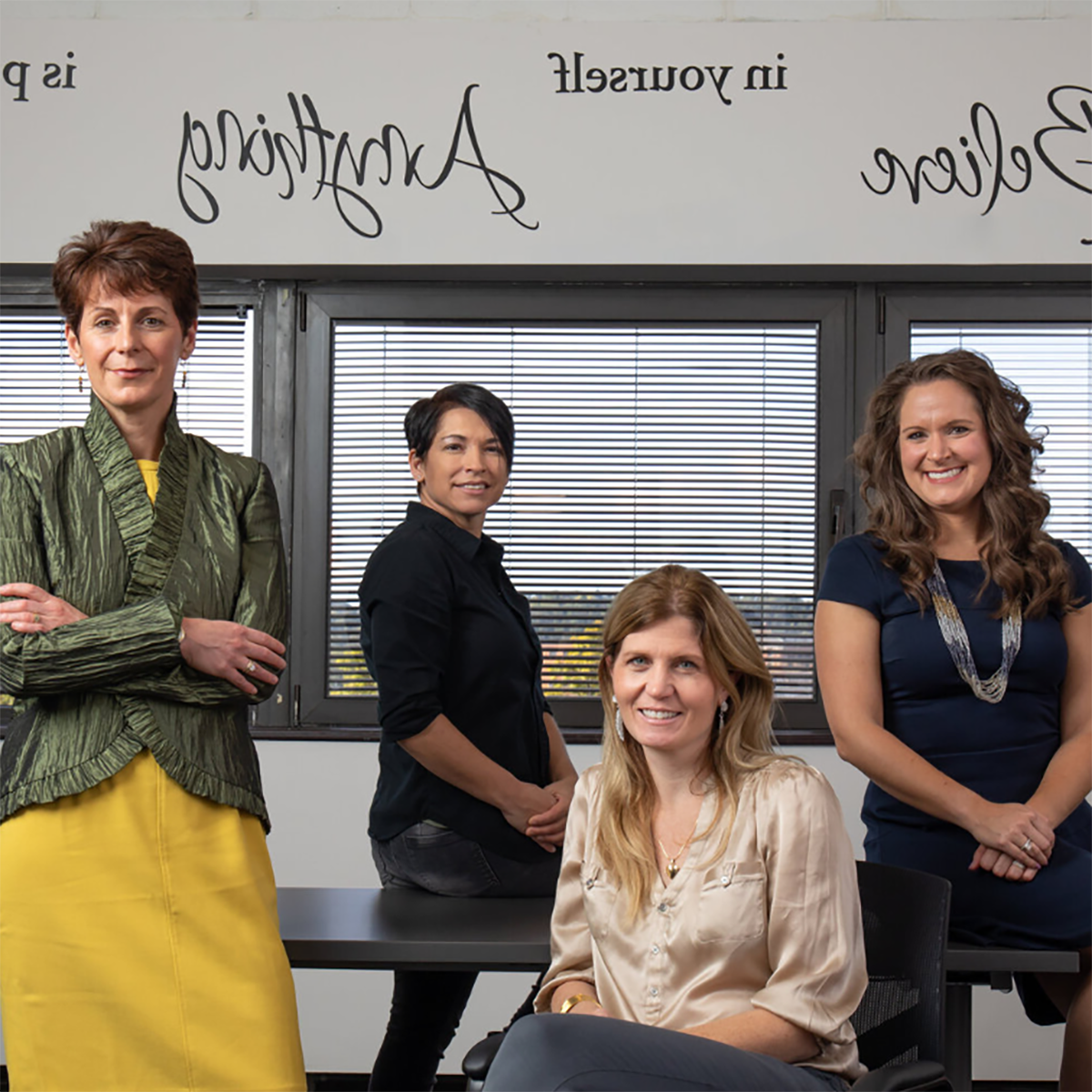 Four women in professional clothing posing for a photo in the Women's Business Center