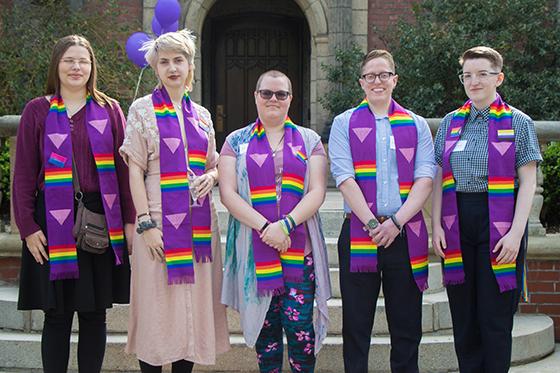 Photo of a group of Chatham University students wearing graduation stoles with rainbow LGBTQ+ representation, posing together for a photo. 